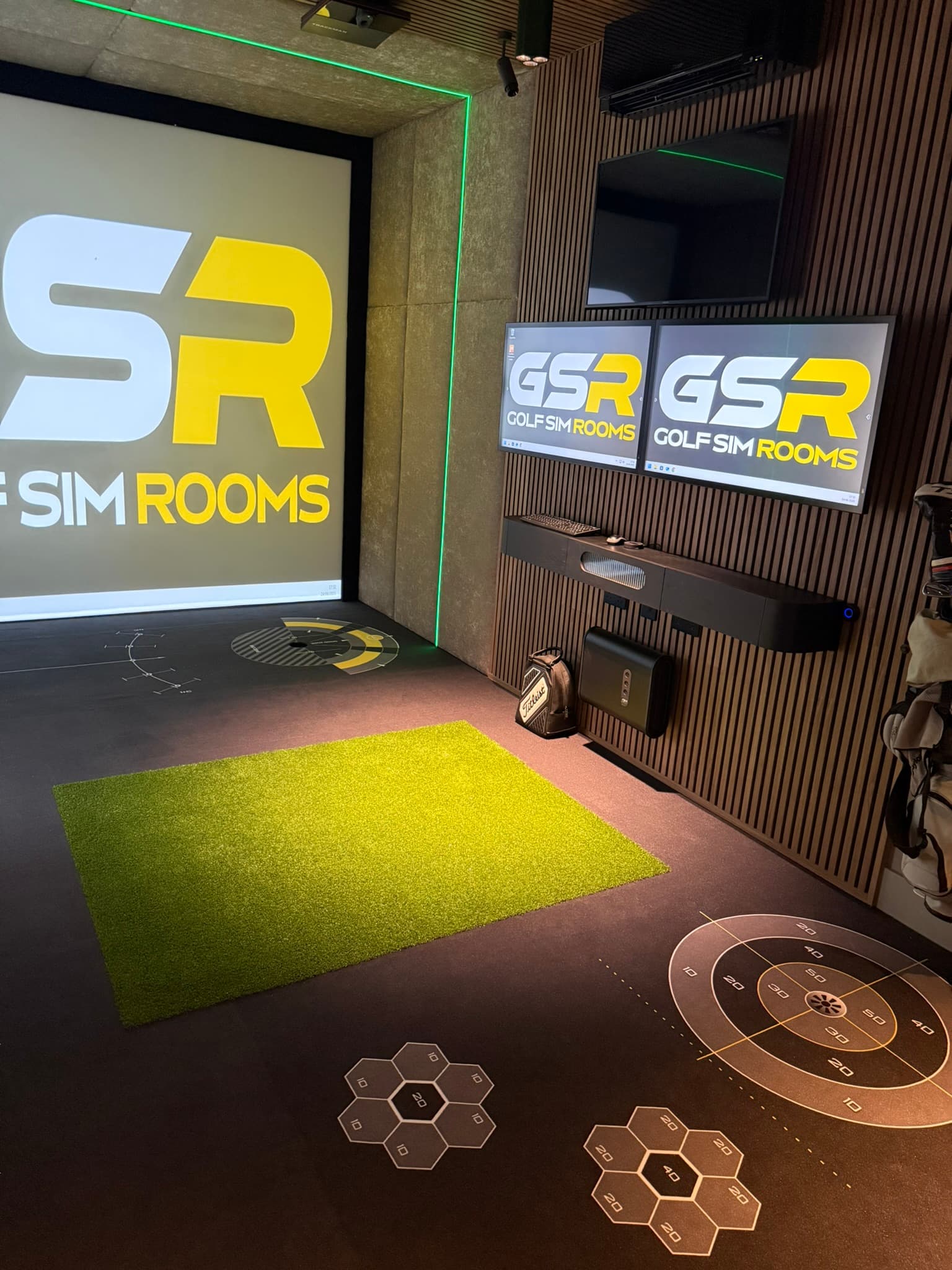 Simulator room with the GSR logo on the screen, two GSR screens on the wall and a printed floor with target markings