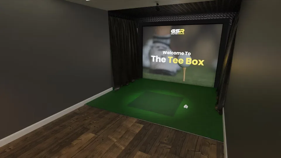 Inside The Tee Box: the simulator screen between dark curtains, with a hitting mat on green turf