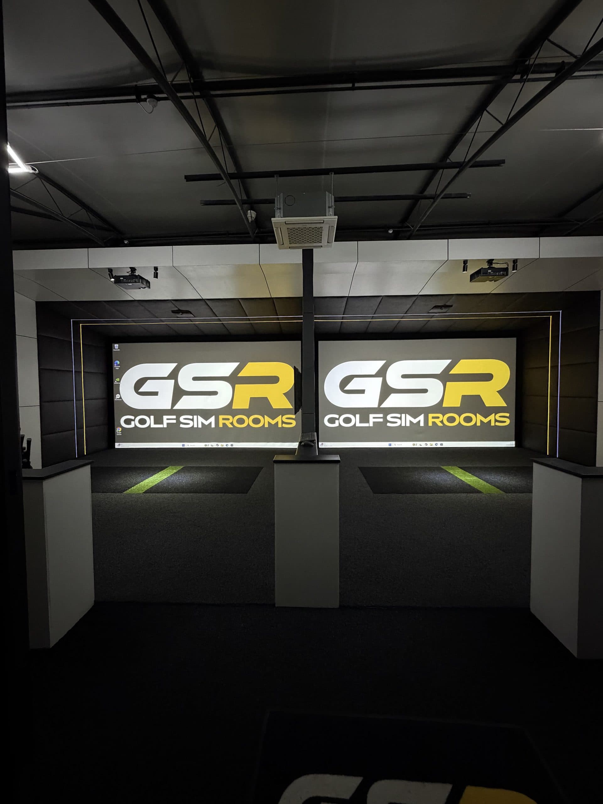 Two simulator bays seen from the back of the room, both showing the Golf Sim Rooms logo