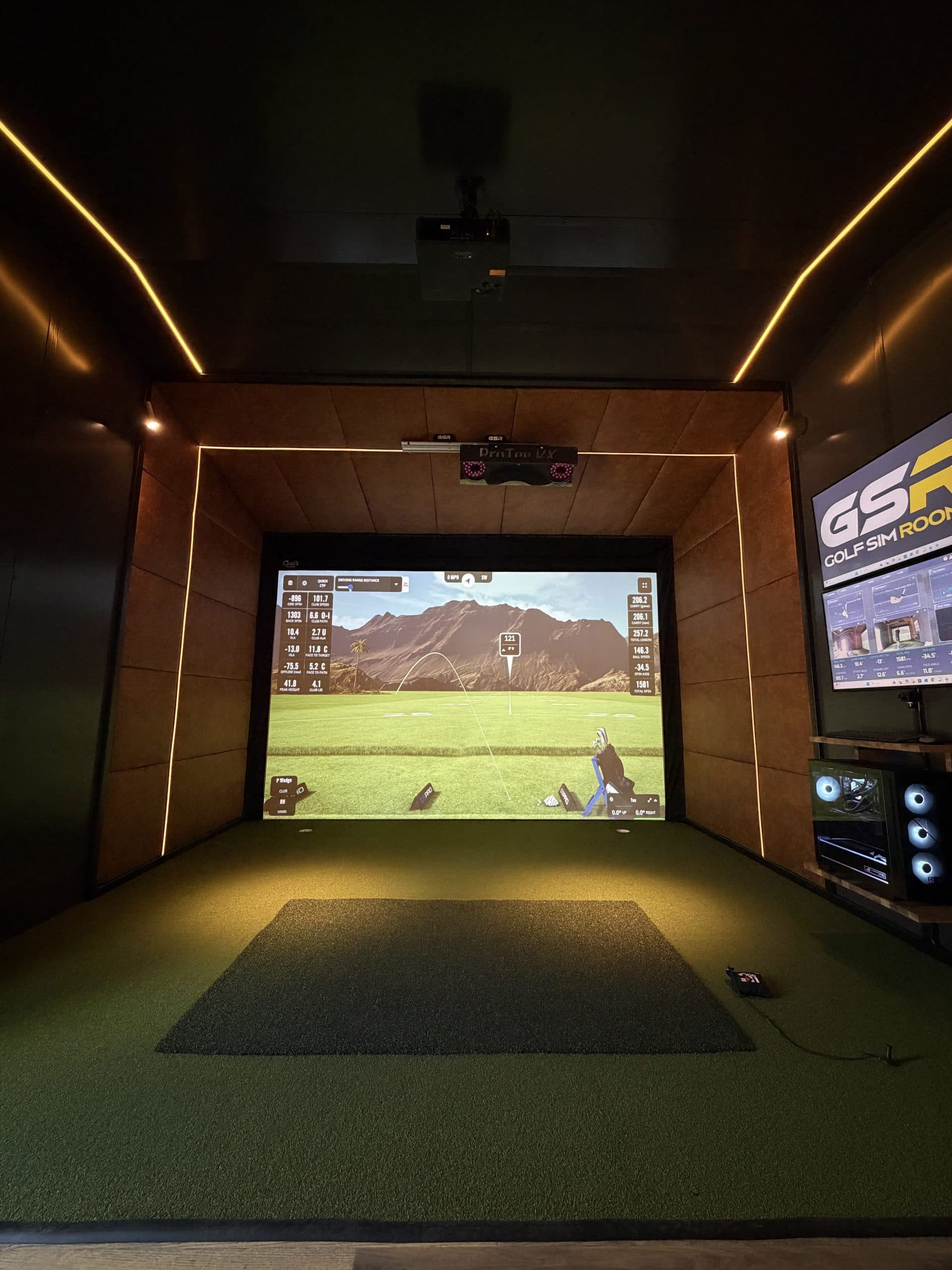 Simulator bay straight on, with the hitting mat, the projector and the wood-framed screen
