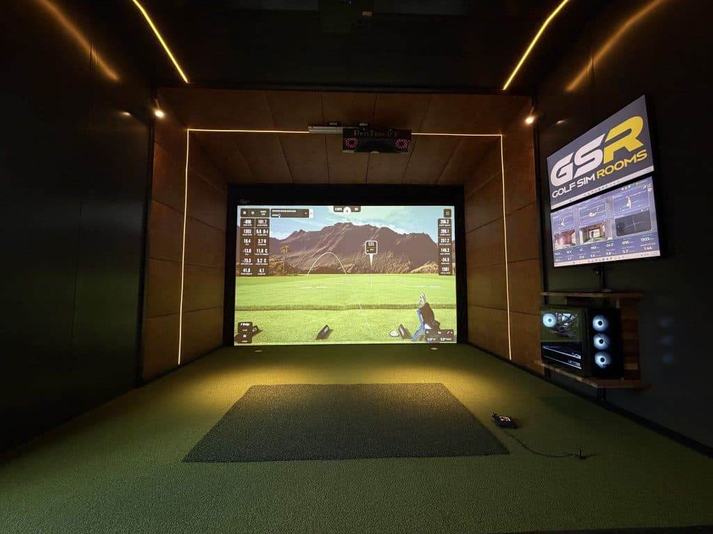 Simulator bay with a mountain course on the screen, a GSR display and a gaming PC on the side wall