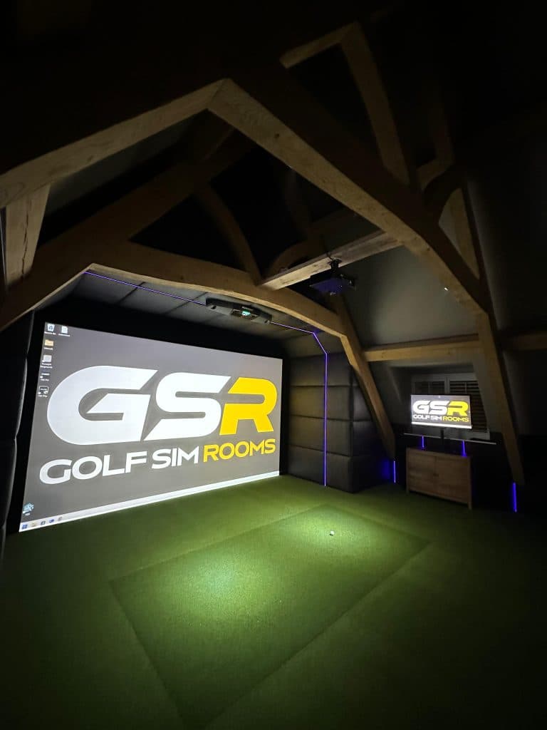 Simulator screen with the GSR logo beneath exposed timber roof trusses, the turf lit in front of it