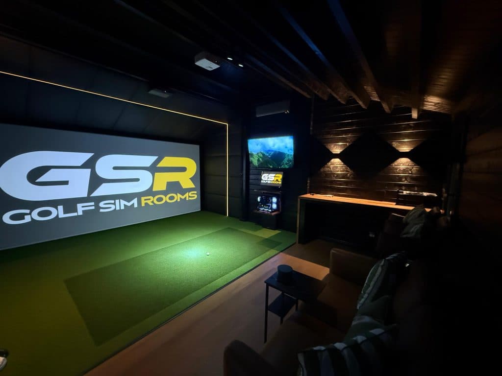 Simulator room with the GSR logo on the screen, a bar counter under wall lights and a sofa at the back