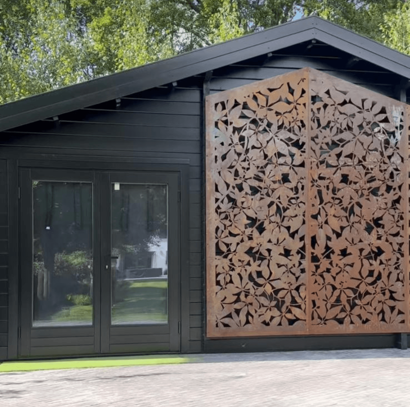 Black log cabin with glass double doors and a rust-coloured decorative screen panel